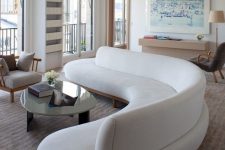 a gorgeous curved white sofa takes over the whole living room and adds soft lines and shapes to it
