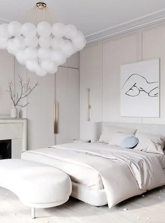 a jaw-dropping contemporary bedroom in neutrals, with an upholstered bed and a curved bench, a fireplace and a fantastic bubble chandelier
