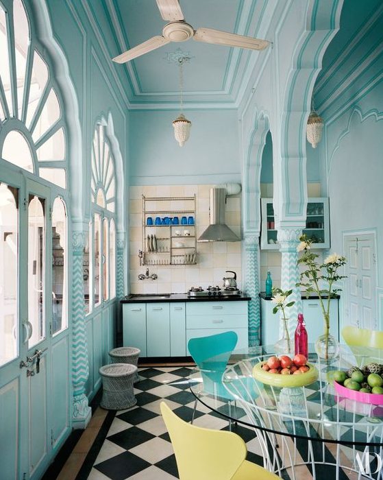 a light blue Moroccan style kitchen with black countertops, a checked floor, a round glass table, yellow and blue chairs