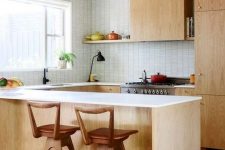 a light-colored mid-century modern kitchen with white countertops and tiled walls plus wooden stools
