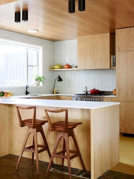 a light colored mid century modern kitchen with white countertops and tiled walls plus wooden stools