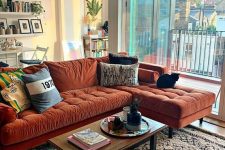 a lovely living room with a rust-colored sectional, a low table, floating shelves and potted plants here and there