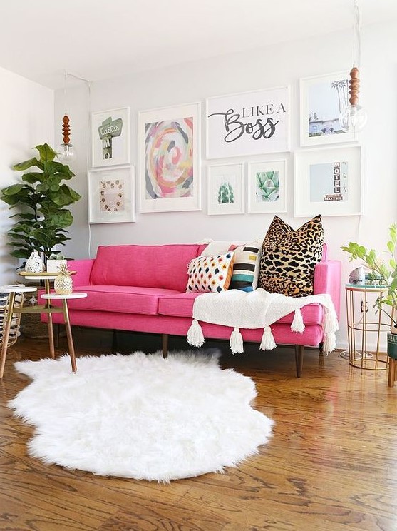 a lovely modern living room done in neutrals, with a pink sofa, an airy gallery wall, white textiles, potted plants and some tables