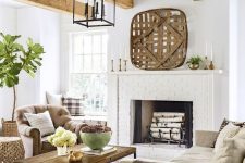 a lovely modern rustic living room with exposed wooden beams and a white brick fireplace, neutral seating furniture and a wooden table