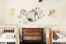 a lovely nursery with a wooden beam on the ceiling, white cribs, a stained dresser, a boho rug and textiles plus baskets for storage
