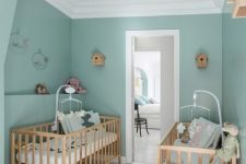 a lovely twin nursery with green walls, matching stained cribs, matching mobiles and a rattan pendant lamp
