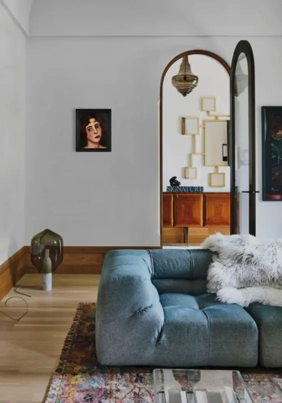 a luxurious living room with a light blue low seat sofa, faux fur, a printed rug and dark artwork is a sophisticated and chic space