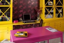 a maximalist home office with bold wallpaper, a hot pink desk and bold yellow storage units, colorful chairs and a pendant lamp
