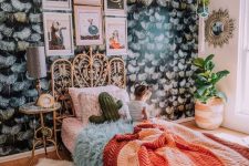 a maximalist sleeping space with a dark accent wall, a rattan bed, a catchy pendant lamp and bright textiles for creating a mood