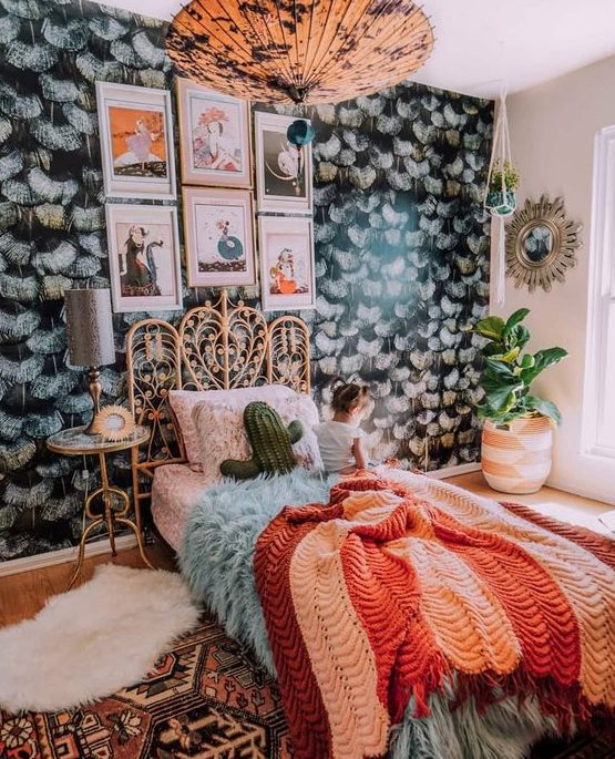 a maximalist sleeping space with a dark accent wall, a rattan bed, a catchy pendant lamp and bright textiles for creating a mood