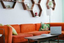 a mid-century modern living room with an orange sofa, hexagon shelves, a low table and colorful pillows is welcoming