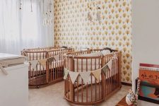 a mid-century modern nursery with an accent wall, matching cribs and buntings, a changing table and matching mobiles