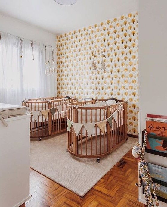 a mid-century modern nursery with an accent wall, matching cribs and buntings, a changing table and matching mobiles