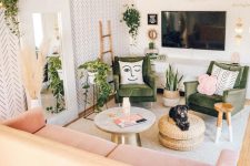 a mid-century modern to boho living room with a TV, a TV unit, potted greenery, a round table, jute poufs and a pink sofa with tassels