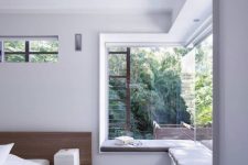 a minimalist bedroom with an upholstered windowsill as a daybed or a seat is a cool idea to catch the views