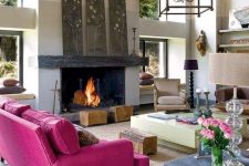 a modern living room with a fireplace, a hot pink sofa, floral artworks, a creative table with wood, tree stumps and catchy lamps