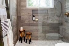 a modern rustic bathroom with tiles that imitate weathered wood, with wodoen stools and a ladder and a window that brings light in
