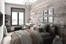 a modern rustic bedroom with a stained wood accent wall, a leather bed, a desk and a white chairs, a sphere chandelier and cool metal sconces