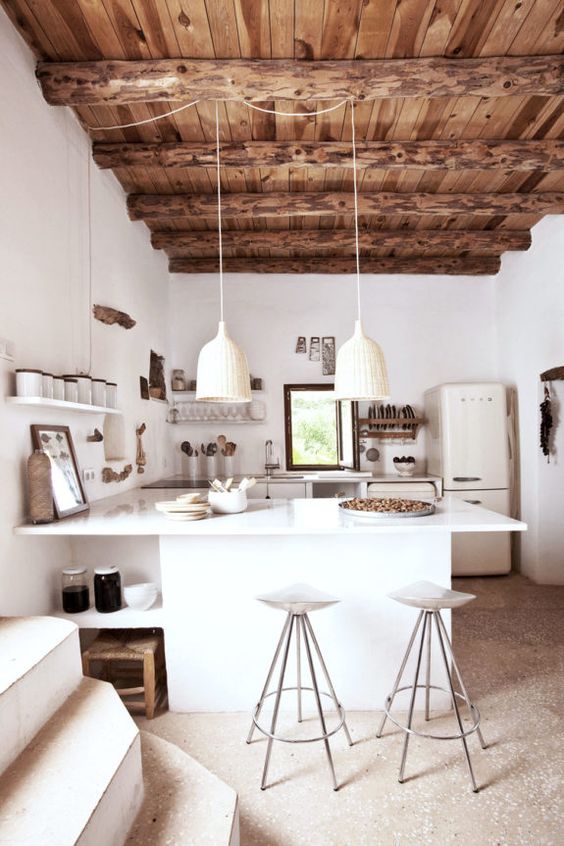 a modern rustic kitchen with a wodoen ceiling and beams, white cabinets, white woven pendant lamps and tall stools