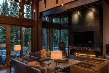 a modern rustic luxurious living room with a double height ceiling and a whole hanging light installation, a fireplace and leather seating furniture