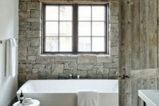a modern rustic meets chalet bathroom with much stone and wethered wood looks chic and airy