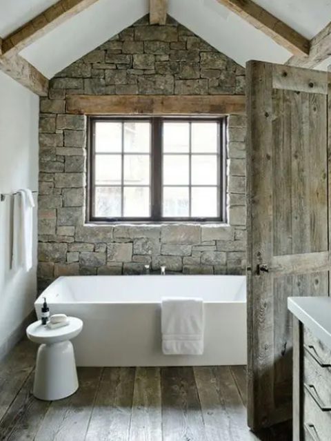 a modern rustic meets chalet bathroom with much stone and wethered wood looks chic and airy
