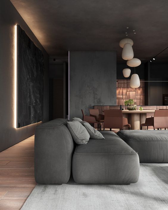 a moody and elegant slate grey space, with a low sofa and daybed, with lit up artworks, pendant lamps and copper furniture