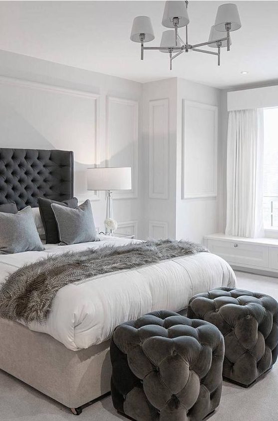 a pair of graphite grey tufted stools by the foot of the bed that match the bed and textiles