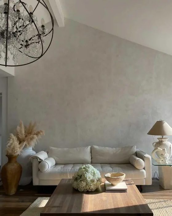 a pretty and airy living room with light grey limewashed walls, a creamy sofa, a low coffee table, pampas grass in vases