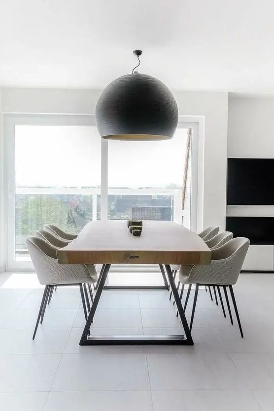 a pretty contemporary dining space with a living edge table, neutral chairs and a statement black pendant lamp is very cool