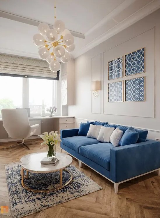 a pretty dove grey and blue living room with a windowsill desk, a creamy chair, a blue sofa and a gallery wall of blue wallpaper, a round table