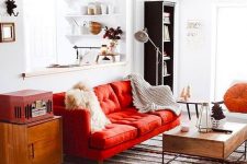 a pretty mid-century modern living room done in neutrals and spruced up with bold touches – a red sofa, a chest and an orange pillow