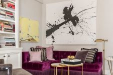 a refined and bold living room with a purple sectional as a centerpiece, a graphic artwork, a built-in bookcase and layered rugs