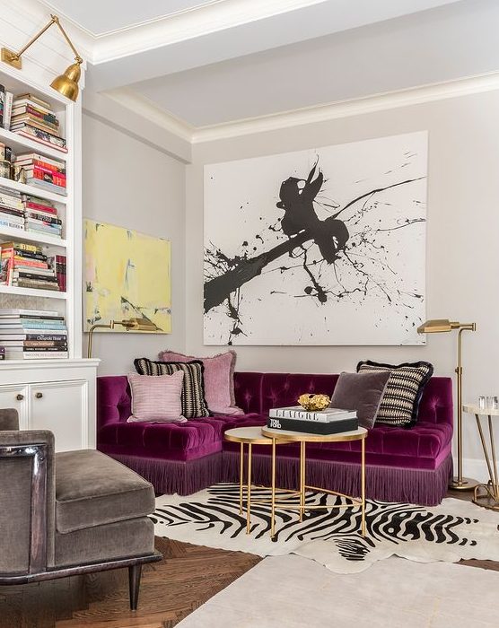 a refined and bold living room with a purple sectional as a centerpiece, a graphic artwork, a built in bookcase and layered rugs