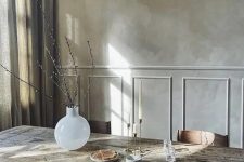 a refined dining room with grey limewashed walls, a rough wooden table, stylish chairs and grey curtains plus a white vase for decor
