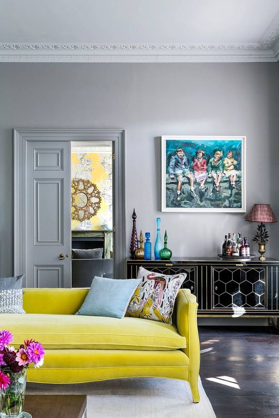 a refined living room with grey walls, a black hexagon credenza, a lemon yellow sofa, bold vases and artwork, a neutral rug