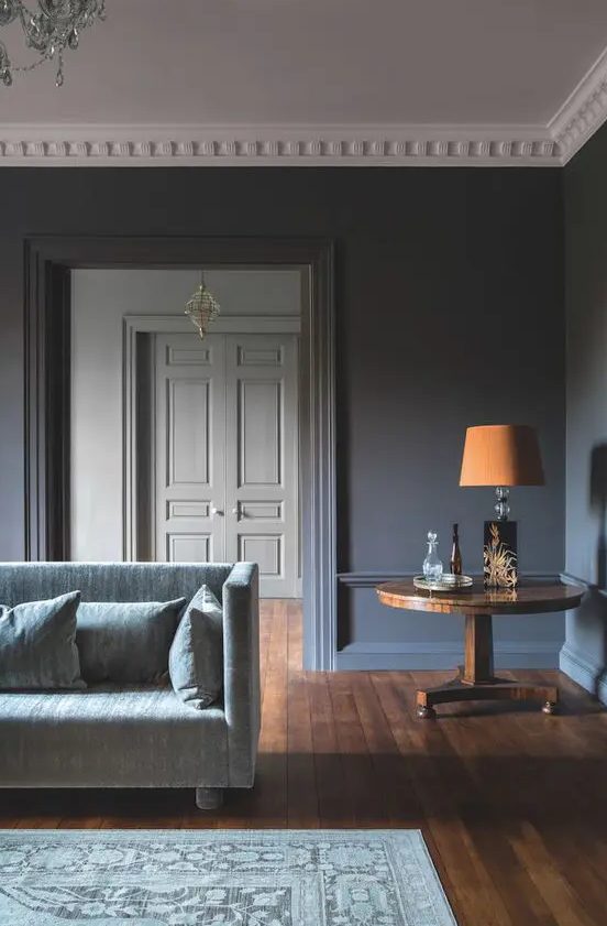 a refined slate grey living room with a grey sofa, a wooden side table with a bold orange lamp is a chic space
