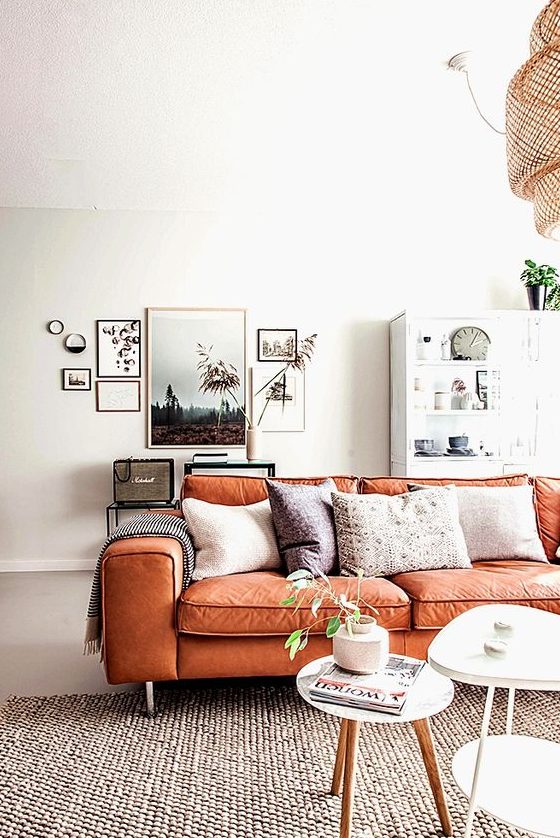 a serene Scandinavian living room with neutral furniture, a chic gallery wall and an orange leather sofa with boho pillows is amazing