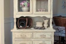 a shabby chic buttermilk cupboard with chicken wire on the former glass compartments is a creative idea for a rustic-infused space
