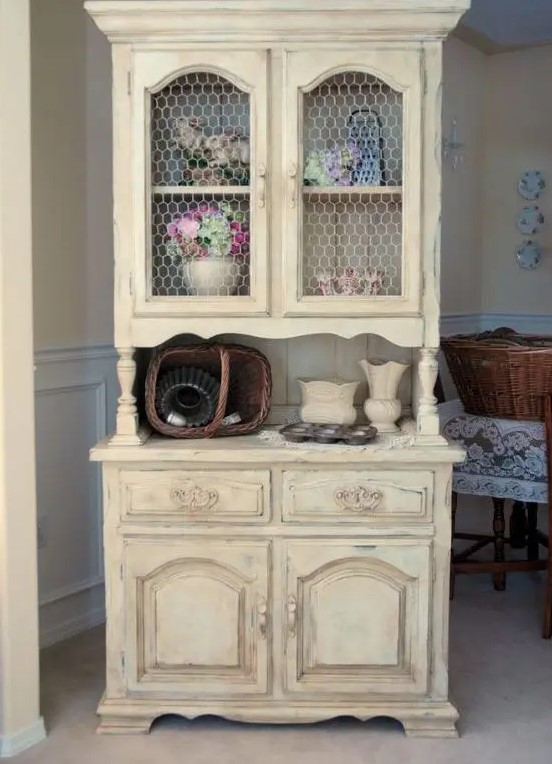 a shabby chic buttermilk cupboard with chicken wire on the former glass compartments is a creative idea for a rustic-infused space