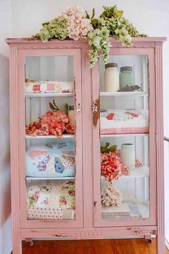 a shabby chic pink cabinet with glass doors and sides is used for storing various textiles and jars is a lovely idea for a girlish shabby chic space