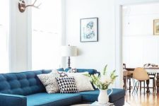 a simple and lovely living room with a blue sofa, a jute rug, a round table and printed pillows is a welcoming space