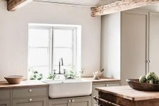 a simple country chic kitchen with a planked ceiling and decorative beams, with grey shaker cabinets and butcherblock countertops, a stained kitchen island