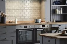 a slate grey kitchen with planks and shaker cabinets, a white subwa tile backsplash, vintage dining furniture