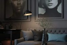 a slate grey living room with a slate grey sofa, oversized artworks, a black console table and a floor lamp, a printed rug