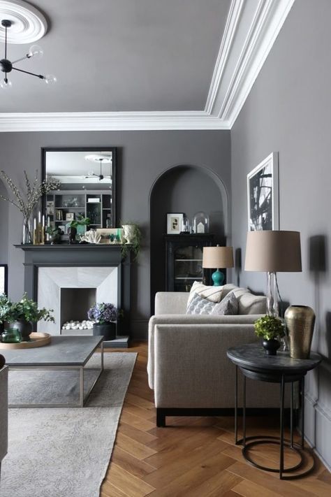 a slate grey living room with an arched niche, a faux fireplace, neutral furniture, chic table lamps and a mid-century modern chandelier