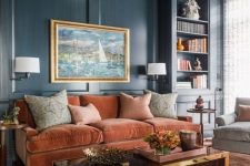 a sophisticated living room with navy walls, a rust-colored velvet sofa, a low polished table, built-in shelves