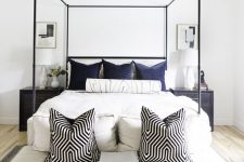 a stylish bedroom with a black frame bed, a large upholstered bench at the foot, a stool and a super cool faceted pendant lamp