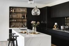 a stylish contrasting kitchen with sleek black cabinets, a white stone kitchen island, built-in shelves and a cluster of pendant lamps