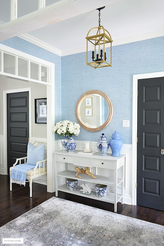 a stylish summer entryway with blue grasscloth wallpaper walls, a white vanity and gold touches plus a printed rug is amazing